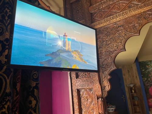 a flat screen tv on a wall with a picture of a lighthouse at SPA La Casa Blue in Wingles