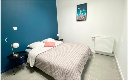 une chambre avec un lit avec un mur bleu dans l'établissement Appartement Terrasse, à Arras