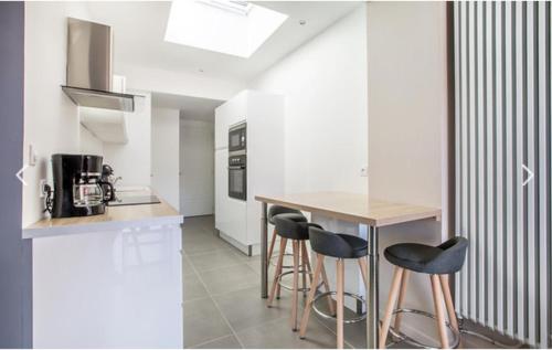 une cuisine avec des murs blancs et un comptoir avec des tabourets dans l'établissement Appartement Terrasse, à Arras