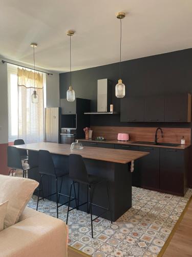 une cuisine avec des armoires noires et un îlot avec des chaises de bar dans l'établissement Superbe appartement 2 chambres plein centre, à Ajaccio