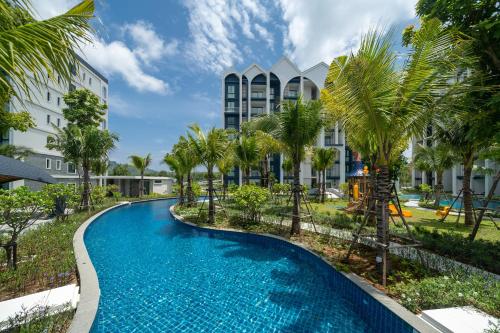 a pool with palm trees in front of a building at The Halo 1 Naiyang Beach in Nai Yang Beach