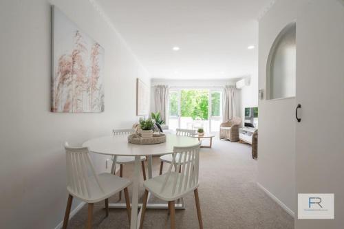 a white dining room with a white table and chairs at QV Stays Gorgeous Hideaway with Spanish Charm in Auckland