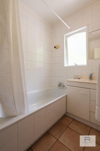 a white bathroom with a tub and a sink at QV Stays Gorgeous Hideaway with Spanish Charm in Auckland