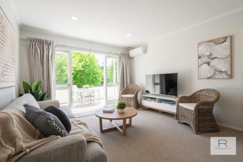 a living room with a couch and a tv at QV Stays Gorgeous Hideaway with Spanish Charm in Auckland
