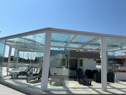 a glass pavilion with chairs and tables on a roof at Acca residence in Terracina