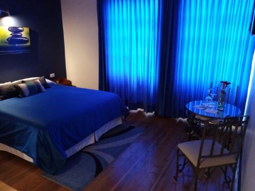 a bedroom with blue curtains and a table and a bed at Hotel Casa Ecuatreasures Centro Historico in Quito