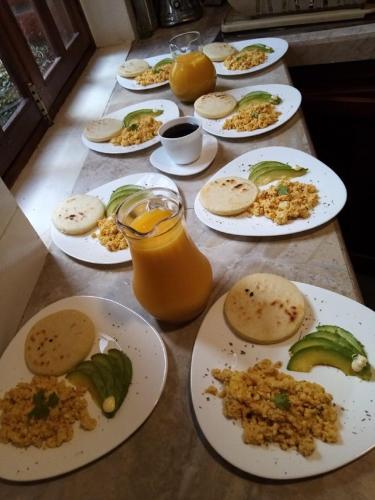 a table topped with plates of food and orange juice at Hotel Casa Ecuatreasures Centro Historico in Quito