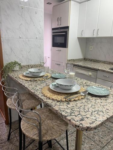 a kitchen with a table with plates and glasses on it at A Orillas del Pilar con parking in Zaragoza