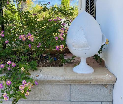a white vase sitting on a ledge next to flowers at Uva Malvasia in Il Monte