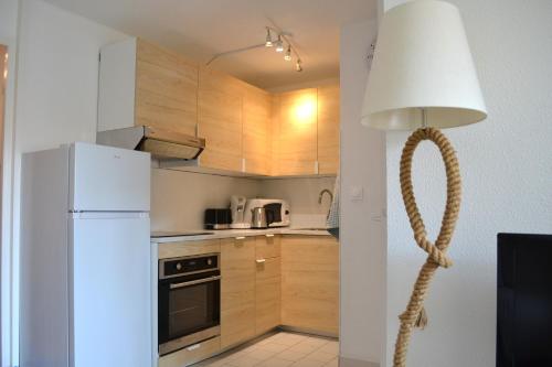 a kitchen with a white refrigerator and a lamp at Le cabanon de Mirza in Sète