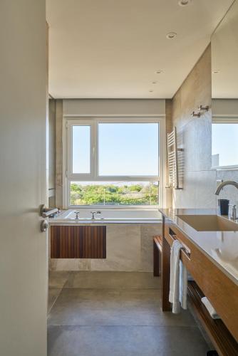 a bathroom with a tub and a sink and a window at Almarena Apart & Hotel Boutique in Costa del Este