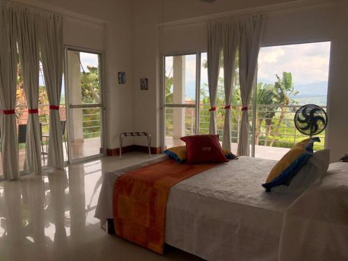 a bedroom with two beds and a large window at Hotel Mirador Las Palmas in Armenia