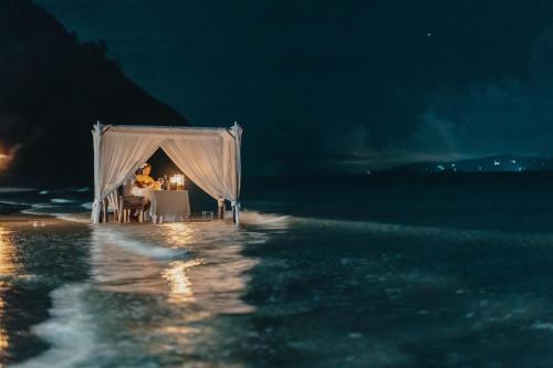 a dinner table in a tent in the water at night at Baan Thong Ching Resort in Khanom