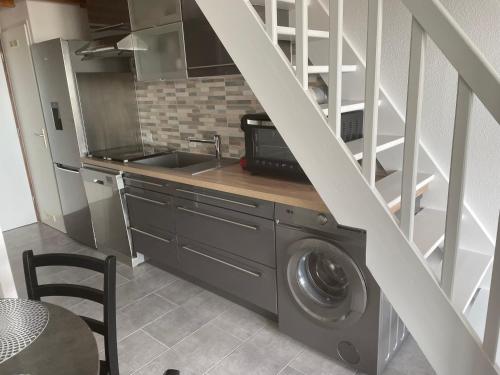 une cuisine avec un lave-linge sous un escalier dans l'établissement appartement vue mer sur la corniche ST Hilaire de riez résidence Sémaphore, à Saint-Hilaire-de-Riez