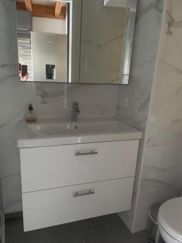 une salle de bain blanche avec un lavabo et un miroir dans l'établissement appartement vue mer sur la corniche ST Hilaire de riez résidence Sémaphore, à Saint-Hilaire-de-Riez