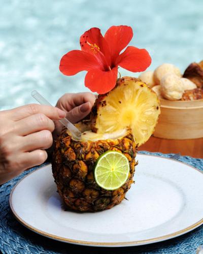 a person eating a pineapple with a flower on it at Almareia Boutique Hotel in Praia dos Carneiros