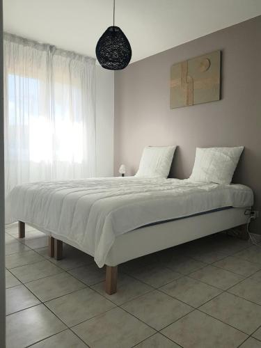 une chambre avec un grand lit blanc avec une fenêtre dans l'établissement Villa Magis, à Vendays-Montalivet