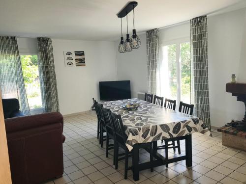 une salle à manger avec une table, des chaises et des fenêtres dans l'établissement Villa Magis, à Vendays-Montalivet