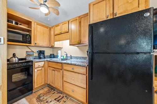 a kitchen with a black refrigerator and wooden cabinets at Gulf Holiday By Beachside Management in Siesta Key