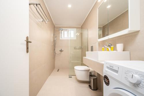a bathroom with a toilet sink and a washing machine at Modern Apartment in the heart of Kos Town in Kos Town