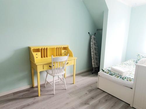 オストルダにあるApartament Parkowyのベッドの横に黄色い机と椅子