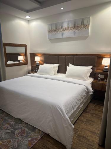 una camera da letto con un letto grande con lenzuola e cuscini bianchi di استديو انيق بدخـول ذاتي ad Al Kharj
