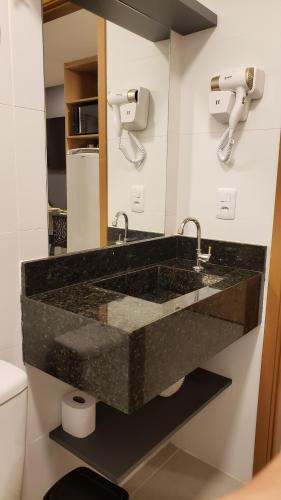 a bathroom with a black marble sink and a mirror at Flat do Gaúcho Porto Prime in Porto De Galinhas