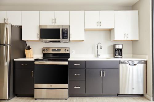 a kitchen with white cabinets and black appliances at Kasa Cadillac Square Detroit in Detroit