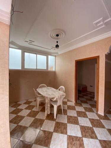 a room with a table and chairs on a checkered floor at Maison à location hay aftas in Mirleft