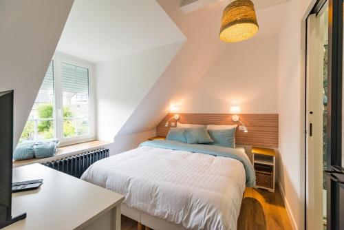 a bedroom with a bed and a desk and a window at Charmante Maison sur le port Loguivy de la Mer in Ploubazlanec