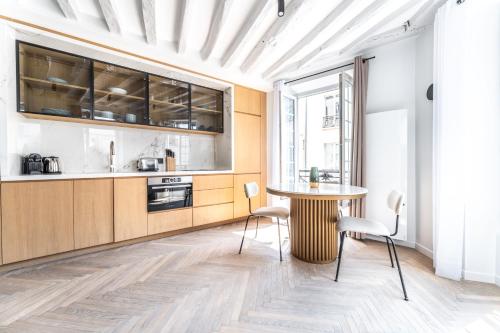 une cuisine avec une table et des chaises dans une pièce dans l'établissement Le Chic Marais Parisien, à Paris