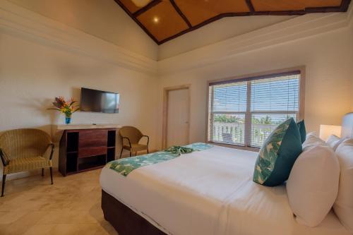 a bedroom with a bed and a desk and a window at Placencia Resort in Maya Beach