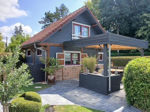 une maison avec un toit en gambrel et une terrasse dans l'établissement Le Chalet de Gonnehem, à Gonnehem
