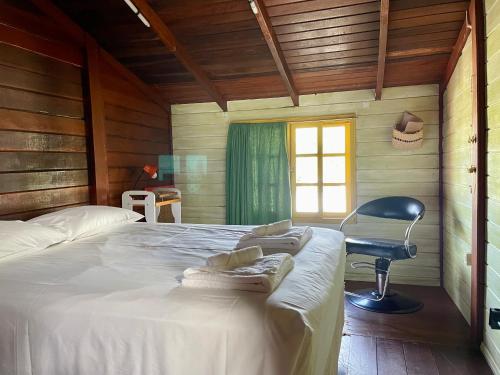a bedroom with a bed and a chair and a window at Casa EcoSpa, Centrinho da Lagoa da Conceição N550 in Florianópolis