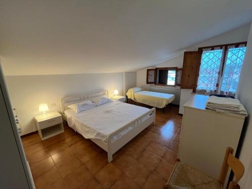 a bedroom with two beds and two tables and two windows at Casa Laura in Porto Garibaldi