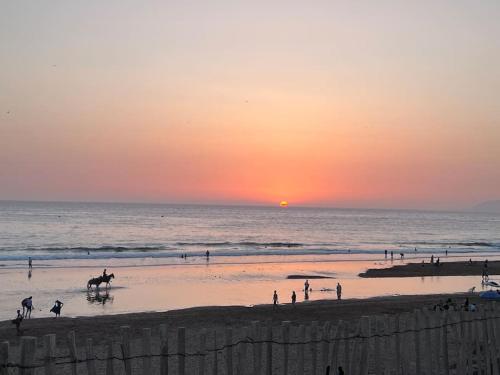 a group of people on the beach at sunset at Appartement No 4 vue sur mer au loin in Tamraght Oufella