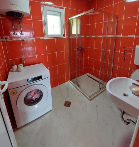 ein rot gefliestes Badezimmer mit einer Waschmaschine und einem Waschbecken in der Unterkunft Darija 1 in Herceg-Novi