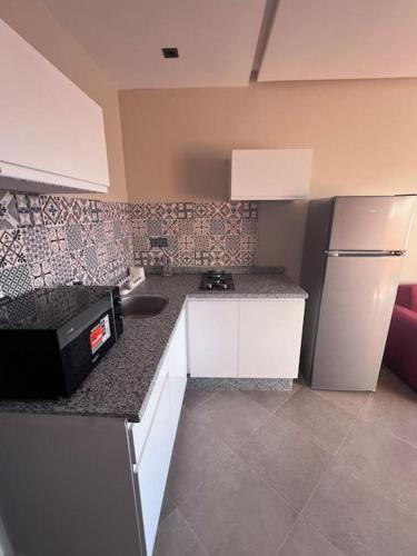 a kitchen with a sink and a refrigerator at Appartement No 4 vue sur mer au loin in Tamraght Oufella