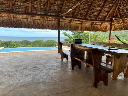 a wooden table and bench in a straw umbrella at Rancho Agua Fria in Jucuarán