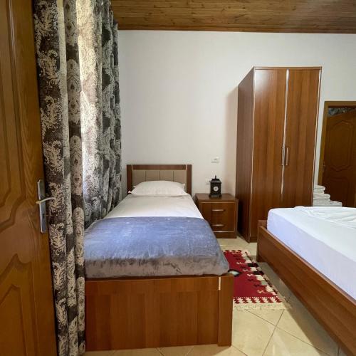 a bedroom with two beds and a curtain at MEROLI Guesthouse - UNESCO quarter in Berat