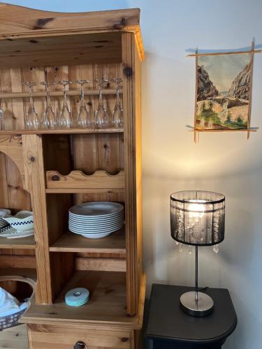 une lampe sur une table à côté d'une armoire avec des verres à vin dans l'établissement Le Plaisancier Bourguignon, à Saint-Fargeau