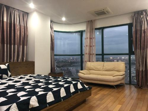 a bedroom with a bed and a chair and large windows at Hana Homestay in Hai Phong
