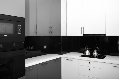 a black and white kitchen with white cabinets and a microwave at Guesthouse - 3 room in Sumqayyt