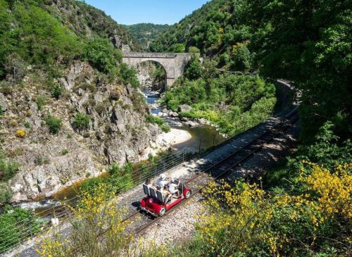 a red train traveling down the tracks near a bridge at Maisonnette à la campagne in Colombier-le-Jeune