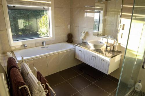 a bathroom with a tub and a sink and a window at Ruru Lodge - Bed and Breakfast in Kinloch