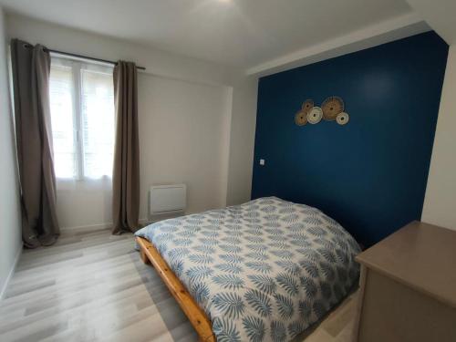 une chambre avec un lit avec un mur bleu dans l'établissement Appartement central Villedieu, à Villedieu-les-Poêles