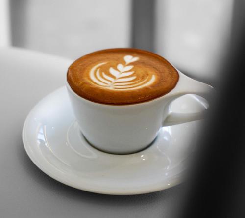 a cup of coffee on a plate on a table at Alhamra Horizons in Al Ḩamrāʼ