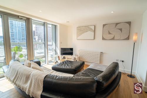 a living room with a leather couch and two chairs at The Canning Comfort in London