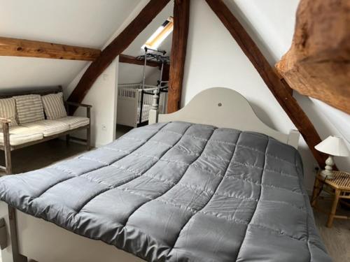 une chambre avec un grand lit dans un grenier dans l'établissement Gîtes la rivière des îles, à Ponthoile