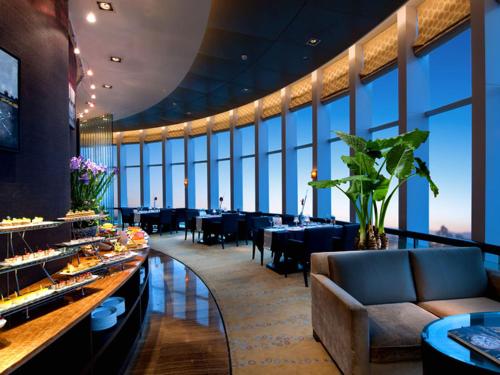 a restaurant with tables and chairs in a room with large windows at HJ International Hotel in Dongguan